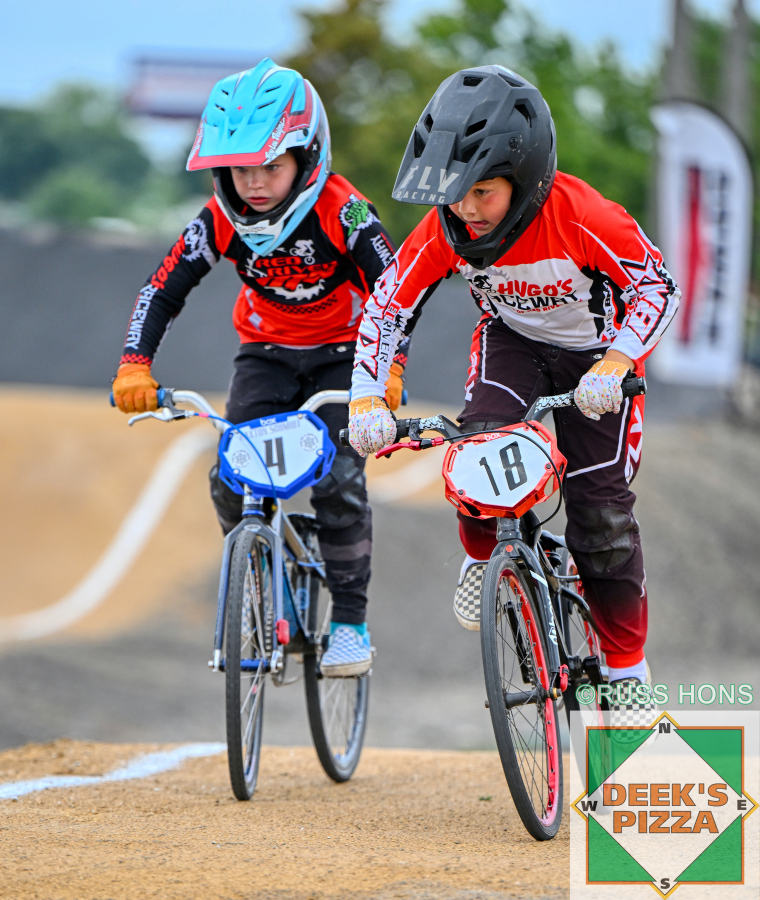 Two BMX riders racing side by side at Hugo's Raceway